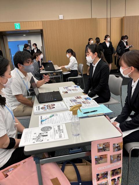 資料や画面を見ながら法人のブースで話を聞く学生